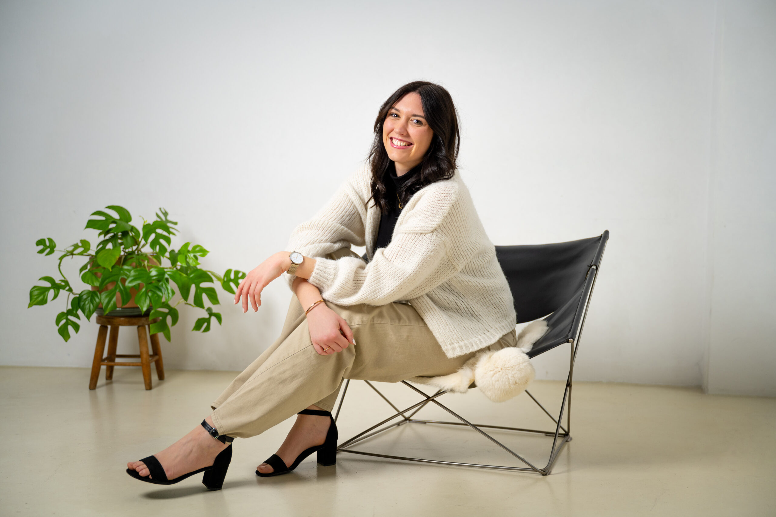 E-Mail Marketing Managerin sitzt strahlend in einem Sessel.